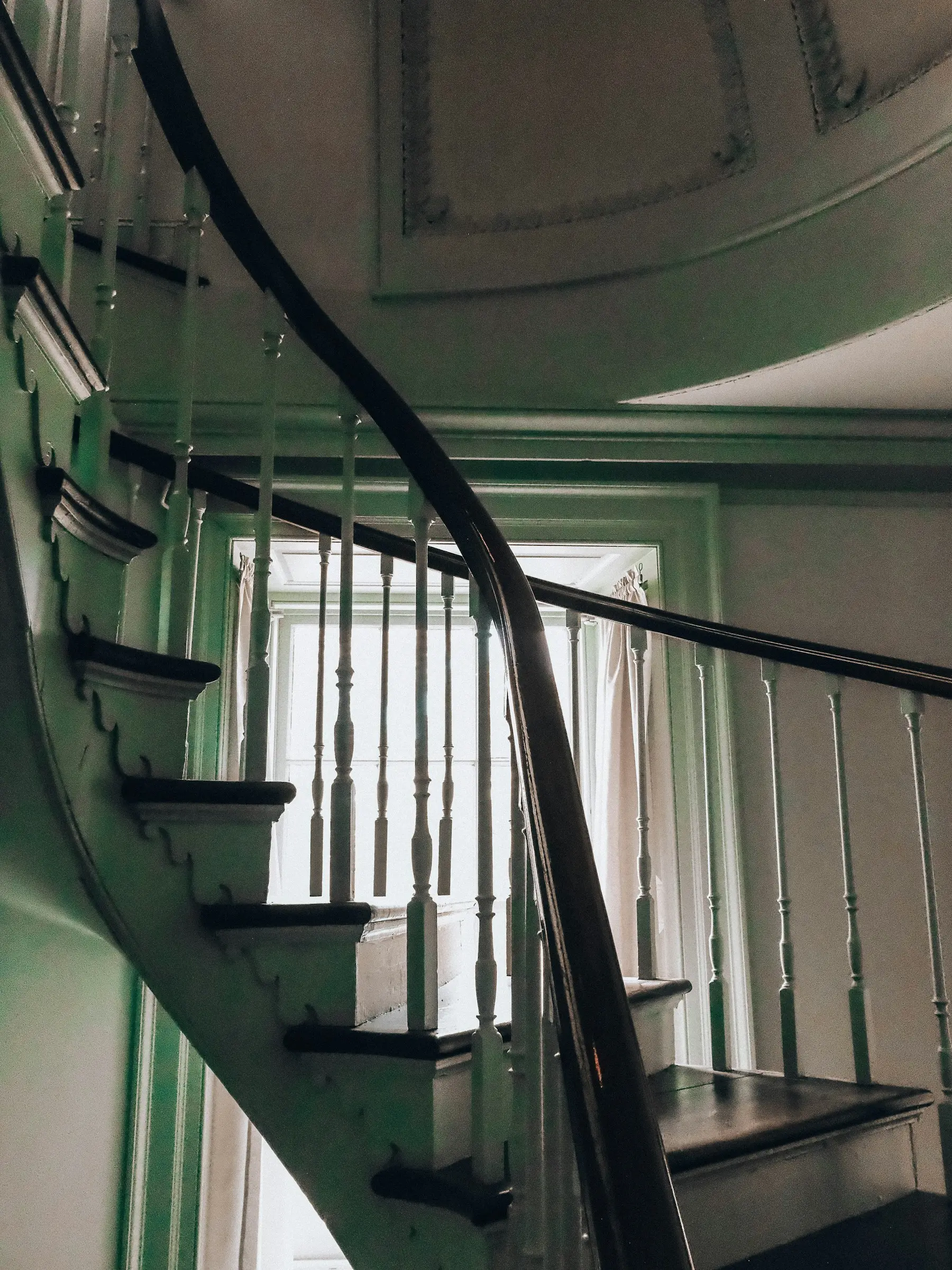 Curved wood handrail with white balusters on a staircase